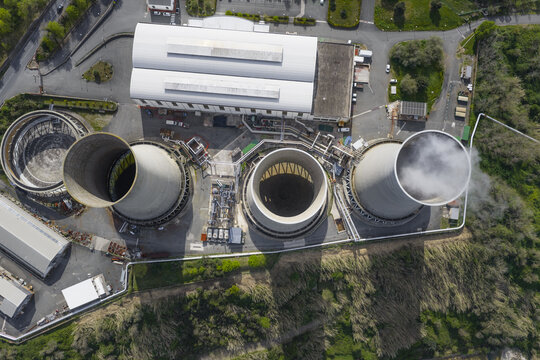 Larderello, Italy - 10 April 2026: Aerial view of Enel Green Power Geothermal Power Plant with its massive cooling towers and industrial facilities surrounded by green hills in Tuscany.