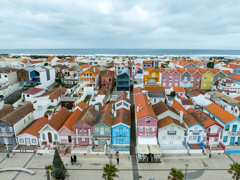 Aerial view of candy-colored houses stand in neat rows against the backdrop of the Atlantic ocean, Costa Nova, Portugal.