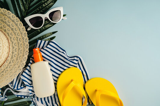 Summer flat lay, beach accessories, sun hat, sun glasses on blue background. Summer holiday background with palm leaf