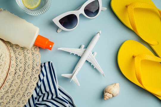 Summer travel holiday concept. Airplane and beach holiday accessories. Blue background flat lay. Top view