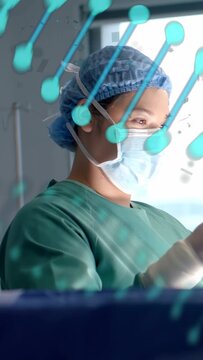 Vertical video: Surgical nurse glancing left reaching across teal decals using forceps for surgery