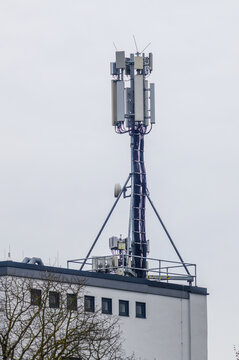 Modern telecommunications tower mounted on a building rooftop with antennas and cables