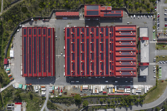 Larderello, Italy - 10 April 2026: Aerial view of Enel Green Power - Centrale Geotermica di Larderello with red rooftops covered in solar panels and surrounding industrial infrastructure.