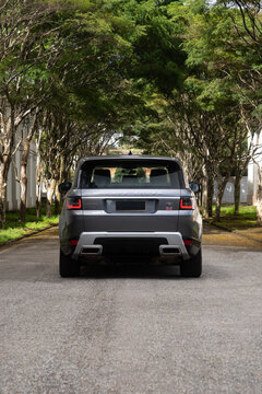 Gray range rover sport rear view outdoors, High performance luxury SUV on city street with trees