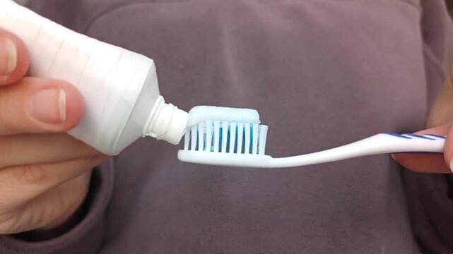 Female hands applying toothpaste on toothbrush close up