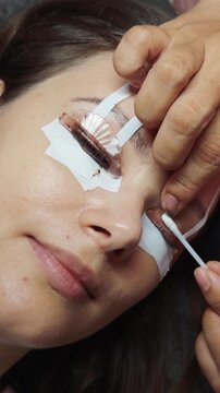 Woman receiving an eyelash lift as a technician applies perming solution to upper lashes for lifted, curled, defined volumebeauty treatment emphasizing care and salon precision