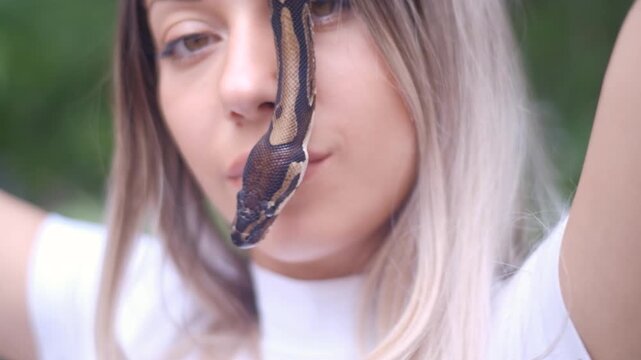 Young woman holding python snake portrait closeup, wild nature concept