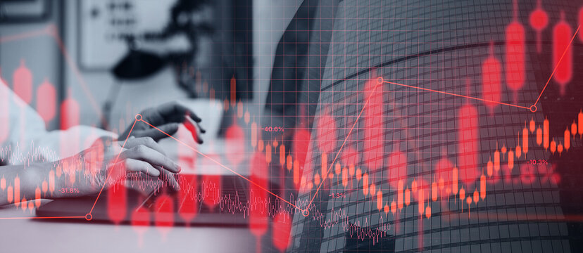 Hands are typing on a computer keyboard while stock market graphs and data overlap in a finance office. The setting shows the hustle of the trading environment.