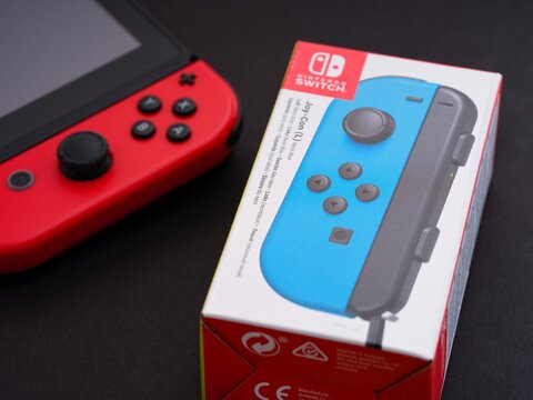 Tambov, Russian Federation - September 28, 2021 A box for new blue Nintendo Switch Joy-Con controller sits next to a Nintendo Switch video game console with red Joy-Con.