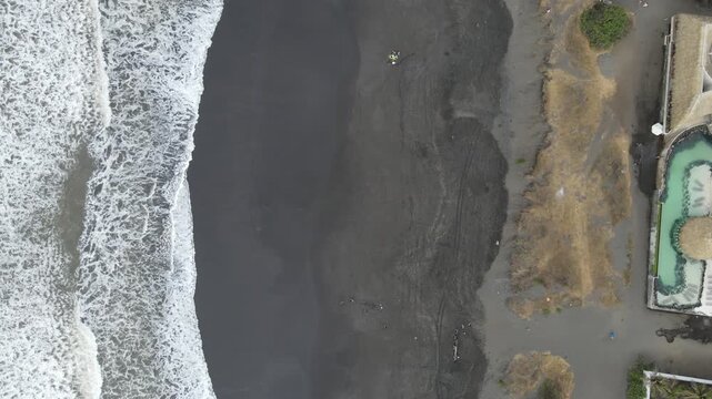 Hermosa vista area desde el Pared&oacute;n Guatemala. A wide of people sitting and playing on the beach at sunset in El Paredon, Guatemala