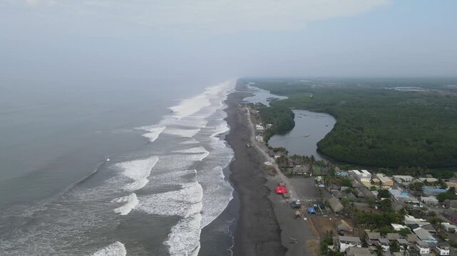 Hermosa vista area desde el Pared&oacute;n Guatemala. A wide of people sitting and playing on the beach at sunset in El Paredon, Guatemala