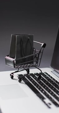 Vertical video: Camera panning up and right moving mini cart carrying two black bags on laptop keys