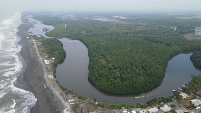 Hermosa vista area desde el Pared&oacute;n Guatemala. A wide of people sitting and playing on the beach at sunset in El Paredon, Guatemala