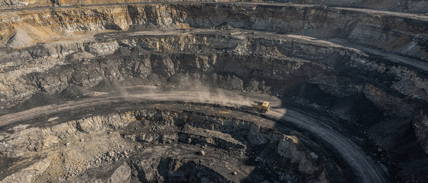 An aerial view of a large open-pit mine showing excavated rock and dirt.