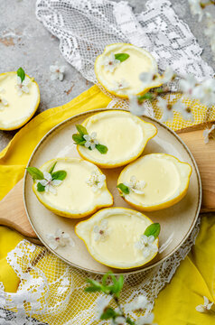 Lemon dessert in a lemon, decorated with flowers and leaves. Lemon dessert. Yellow dessert. Lemon Kurd.