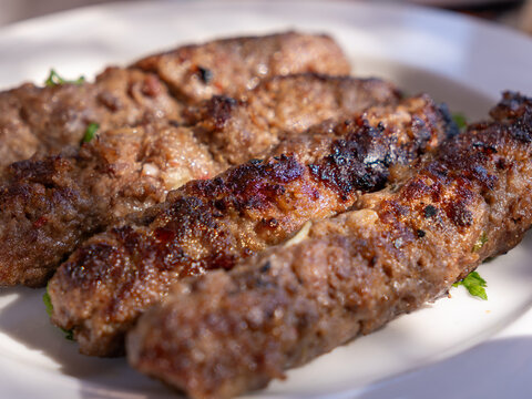 Close-up of juicy grilled Egyptian kofta skewers served on a white plate. Middle Eastern street food and travel cuisine concept.