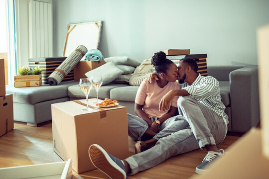 Young couple kissing while unpacking in new apartment living room