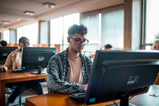 Focused student working on desktop in university computer lab