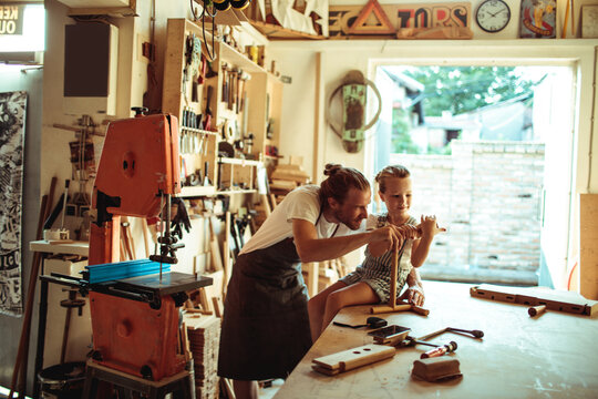 Father teaching daughter woodworking in home workshop