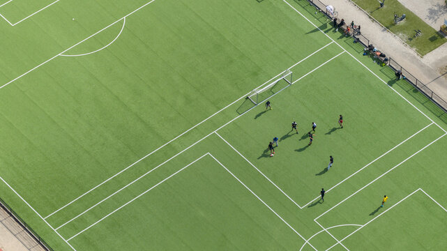 Aerial view of people playing a match on a green artificial turf soccer pitch with white markings Amsterdam, Noord-Holland, Netherlands.