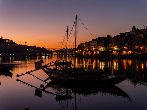 Rabelo boat reflecting on douro river at sunset in porto
