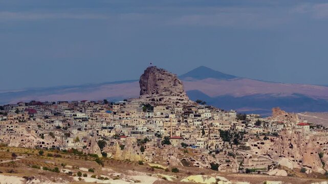 Aerial view of Uchisar Castle rising above Cappadocia landscape in Turkey, surrounded by unique rock formations and valleys under a dramatic cloudy sky