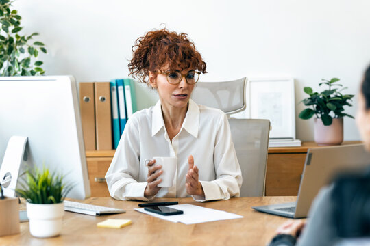 Cheerful businesswoman talking with her partner while working in the office