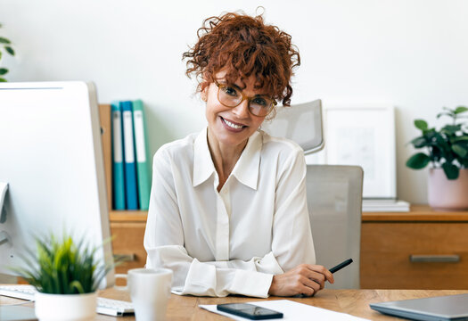Elegant mature businesswoman looking at camera while working in the office