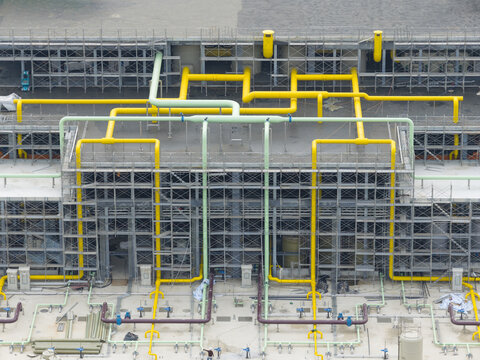 Aerial view of complex industrial yellow and green piping systems integrated with metal scaffolding at a construction site in Taiwan.