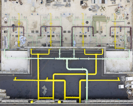 Aerial view of a complex industrial piping system with yellow and green pipes on a construction site in Taiwan.