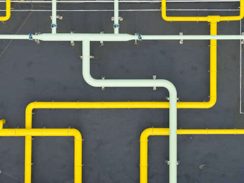 Aerial view of yellow and light green industrial pipes over a dark wastewater treatment tank in Taiwan.
