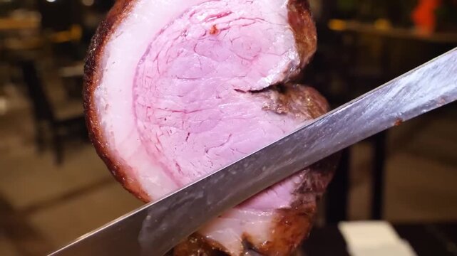 close-up shot of a succulent, medium-rare Picanha steak on a traditional metal skewer being expertly carved with a sharp knife in a Brazilian steakhouse. The footage highlights the glistening fat cap 