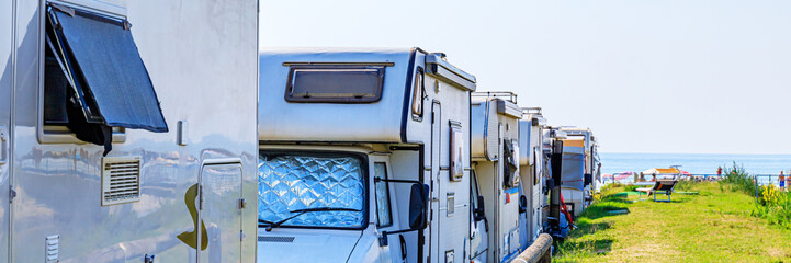 RVs parked by the beach with the ocean in view on a sunny day during summer