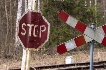 Zniszczony znak stop z dziurami po kulach stoi w pobliżu przejazdu kolejowego w zalesionym terenie niedaleko Ostrowca. Znak jest zamontowany na metalowym słupie, noszącym ślady rdzy i upływu czasu.  © Grzegorz