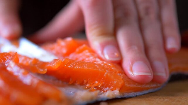 Extreme Close-Up Hands Slicing Fresh Salted Salmon Fillet with Knife on Wooden Board &mdash; Seafood Preparation Omega-3 Nutrition and Healthy Cooking Concept