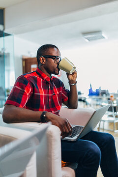 Young professional drinking coffee while working on laptop