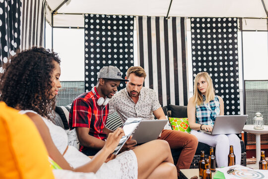 Young adults using laptops and tablet at outdoor lounge