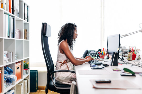 Focused woman working at computer in bright office desk