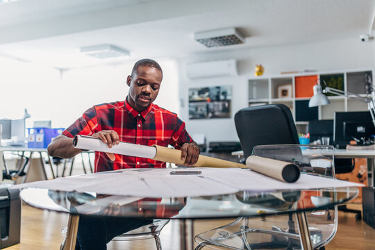 Architect unrolling blueprint in modern design studio office