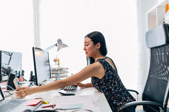 Woman stretching at desk in bright modern office workspace