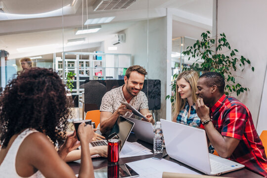 Diverse team brainstorming with laptops in modern office