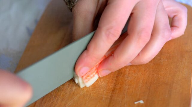 Chopping Imitation Crab Sticks with Green Knife, Close-up Surimi Seafood Preparation for Healthy Salad, Home Kitchen Cooking and Meal Prep Action