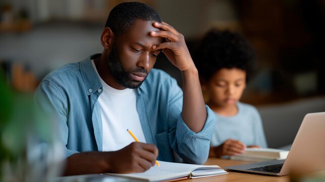 Faceless sad father sitting with a tired expression at a table during his son's failed mathematics homework in a family education stress concept. Defocused home background. Sad