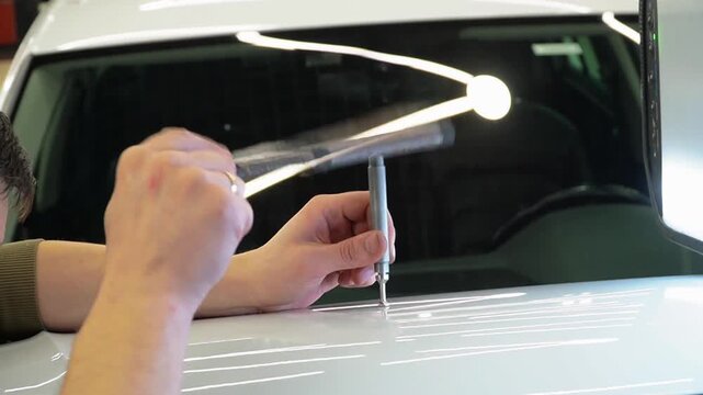 Body repair. A specialist repairs a dent on the car body without painting. Paintless Car Dent Repair. PDR. Process of paintless dent repair on car body. The mechanic at the auto shop with tools. 