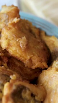 Fried fish or meat in batter is served on a blue plate, with a side plate of cheese and Easter eggs nearby. Close-up of a festive table setting with traditional homemade dishes and holiday atmosphere.