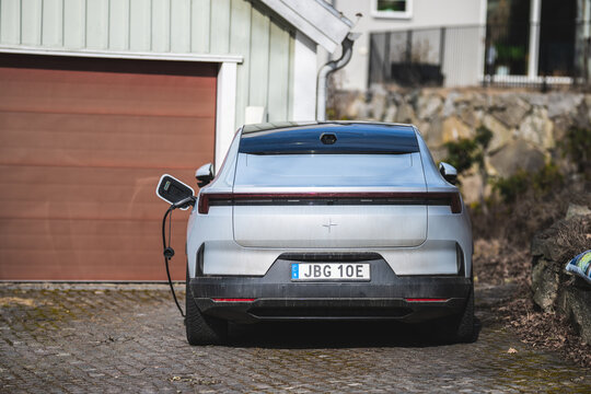 Kungsbacka, Sweden - March 20 2026: Silver Polestar 4 electric car charging at home driveway in suburban setting.