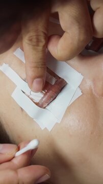 Woman undergoing an eyelash perm at a salon, receiving professional beauty care as an aesthetician applies solution to curl and lift natural lashes onto a silicone pad, enhancing eye appearance
