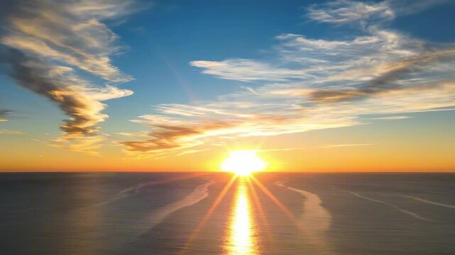 Expansive dawn seascape with painterly cloud formations, winding tidal textures, distant horizon fire, and tranquil ocean surface glowing beneath a vivid sunrise sky of coral and blue with calm