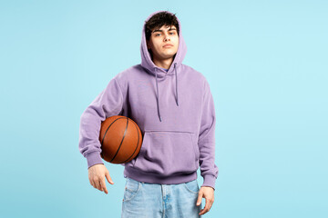 Obraz premium Teenager holding basketball wearing purple hoodie