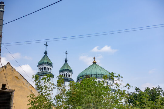  two green domes on top of a building with a cross on top, green unfolds beneath the open sky across Soala, Romania